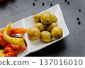 Green olives appetizer served on white plate with Mediterranean antipasti composition 137016010