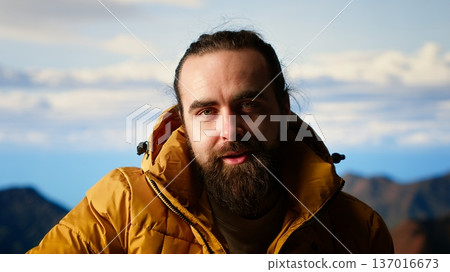 Explorer embraces the thrill of reaching a mountain summit and relaxing, feeling the fresh air and panoramic beauty. Hiker being excited and tired, proud of self improvement and goals. Camera B. Explorer embraces the thrill of reaching a mountain summit and relaxing, feeling the fresh air and panoramic beauty. Hiker being excited and tired, proud of self improvement and goals. Camera B. 137016673