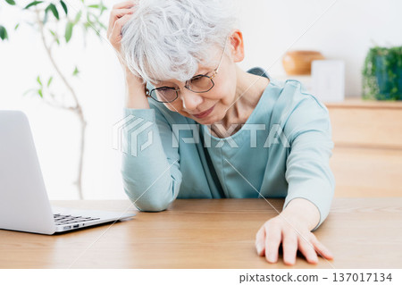 一位老年婦女在電腦前感到身體不適。 137017134