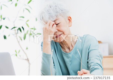 一位老年婦女在電腦前感到身體不適。 137017135