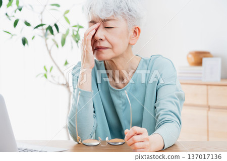 一位老年婦女在電腦前感到身體不適。 137017136