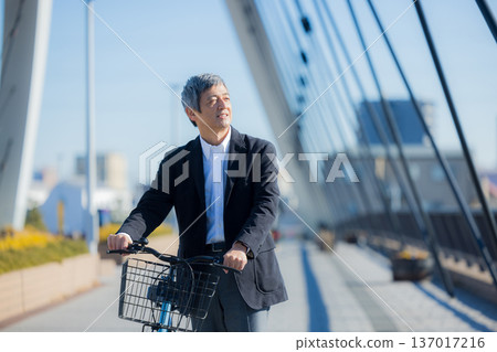 一名六十多歲的男子推著自行車行走 137017216