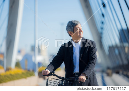 一名六十多歲的男子推著自行車行走 一名六十多歲的男子推著自行車行走 137017217