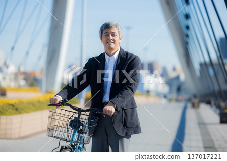 一名六十多歲的男子推著自行車行走 137017221