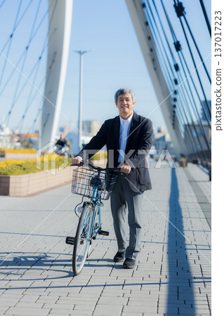 一名六十多歲的男子推著自行車行走 137017223