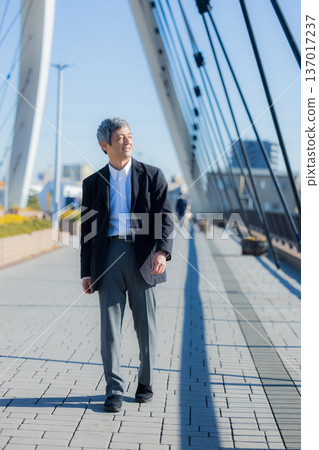 A man in his 60s walking while pushing a bicycle 137017237