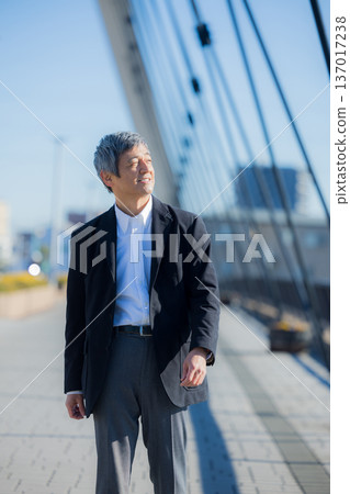 A man in his 60s walking while pushing a bicycle 137017238