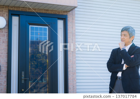 一位六十多歲的男子站在公司大樓前沉思。 一位六十多歲的男子站在公司大樓前沉思。 137017784