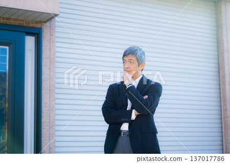 A man in his 60s thinking in front of the company building 137017786