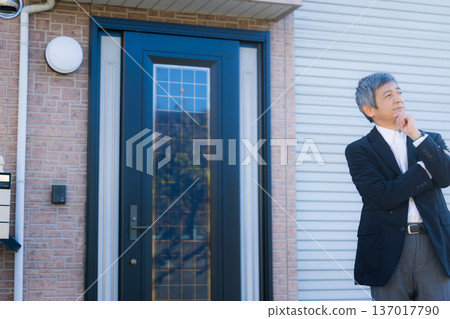 A man in his 60s thinking in front of the company building A man in his 60s thinking in front of the company building 137017790