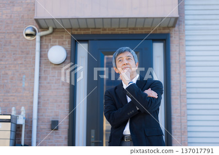 一位六十多歲的男子站在公司大樓前沉思。 137017791