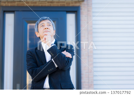 A man in his 60s thinking in front of the company building 137017792