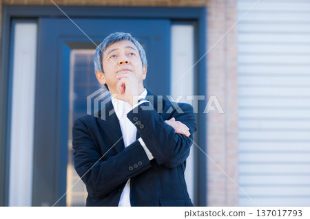 一位六十多歲的男子站在公司大樓前沉思。 137017793