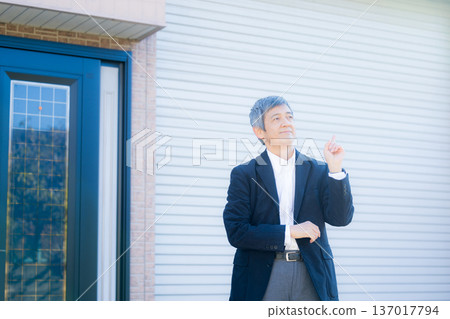 一位六十多歲的男子站在公司大樓前沉思。 137017794
