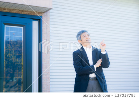 A man in his 60s thinking in front of the company building 137017795