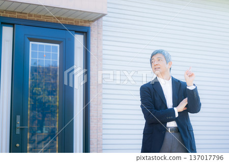 一位六十多歲的男子站在公司大樓前沉思。 一位六十多歲的男子站在公司大樓前沉思。 137017796