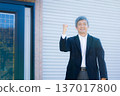一位六十多歲的男子站在公司大樓前沉思。 137017800