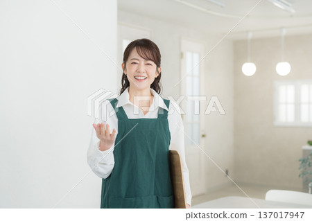 A woman with a smile wearing an apron 137017947