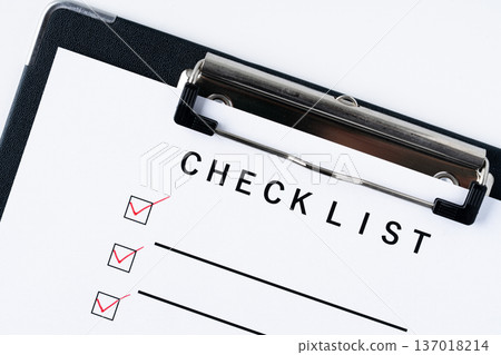Close-up of a checklist paper in a binder with red ticks 137018214