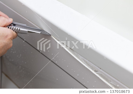 用美工刀清除浴室浴缸上的舊填縫劑 137018673
