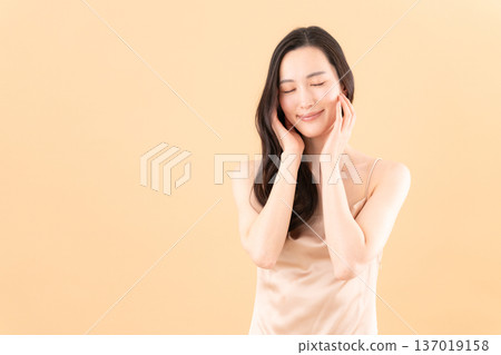 Beauty image of a woman doing skin care on a beige background 137019158