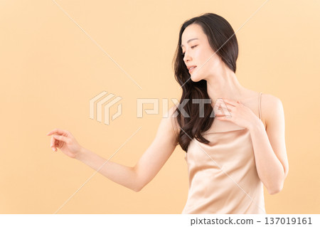 Beauty image of a woman doing skin care on a beige background 137019161