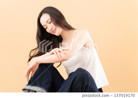 Beauty image of a woman doing skin care on a beige background 137019170