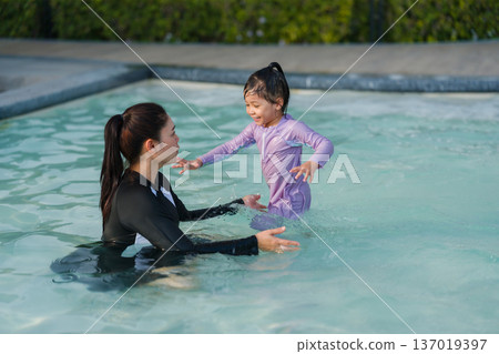 preschool child girl playing and swimming with her mother in pool 137019397