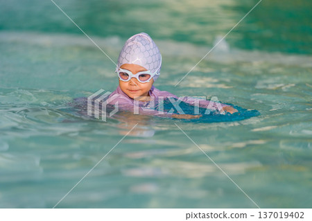 preschool child girl learning to swim with board in swimming pool preschool child girl learning to swim with board in swimming pool 137019402