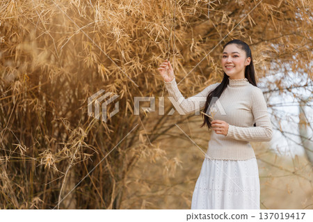 Beautiful woman posing among dry bamboo branches forest in nature. 137019417