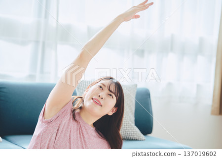 Healthy habits of a woman in her 30s stretching at home Healthy habits of a woman in her 30s stretching at home 137019602