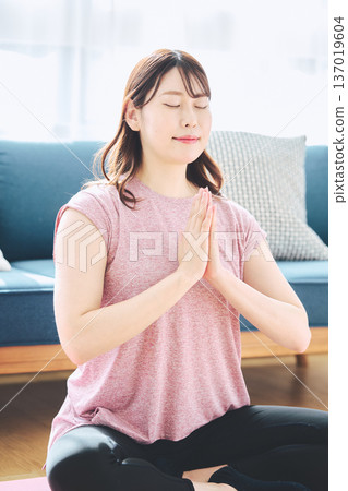 一位30多歲的女性在家中進行冥想和深呼吸，實踐正念生活方式。 137019604