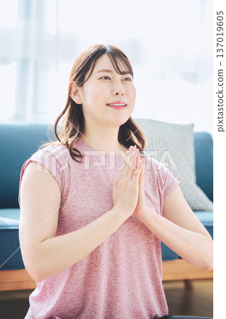 一位30多歲的女性在客廳做瑜伽，展現她的健身生活 137019605