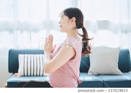 一位30多歲的女性在客廳做瑜伽,展現她的健身生活 一位30多歲的女性在客廳做瑜伽,展現她的健身生活 137019615