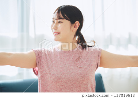 一位30多歲的女性在客廳做瑜伽，展現她的健身生活 137019618