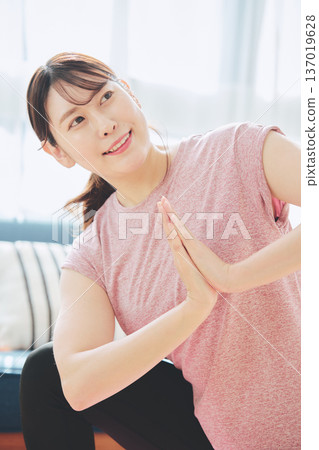 一位30多歲的女性在客廳做瑜伽,展現她的健身生活 一位30多歲的女性在客廳做瑜伽,展現她的健身生活 137019628