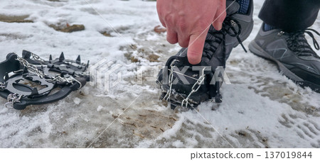 Crampons for shoes for walking on icy surfaces and winter mountain trips. Essential equipment for safe hiking on icy trails. High quality photo Crampons for shoes for walking on icy surfaces and winter mountain trips. Essential equipment for safe hiking on icy trails. High quality photo 137019844