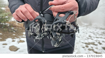 Crampons for shoes for walking on icy surfaces and winter mountain trips. Essential equipment for safe hiking on icy trails. High quality photo Crampons for shoes for walking on icy surfaces and winter mountain trips. Essential equipment for safe hiking on icy trails. High quality photo 137019845