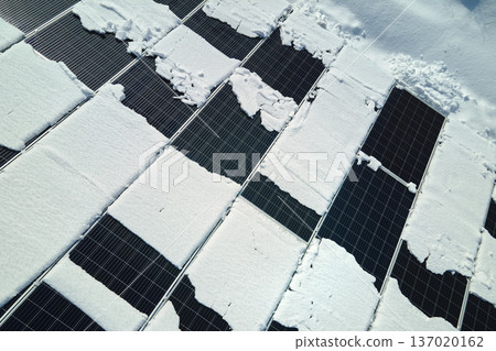 Aerial view of electrical power plant with solar panels covered with snow melting down in winter end for producing clean energy. Concept of low effectivity of renewable electricity in northern region Aerial view of electrical power plant with solar panels covered with snow melting down in winter end for producing clean energy. Concept of low effectivity of renewable electricity in northern region 137020162