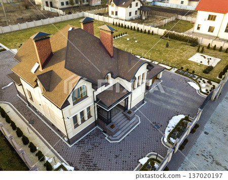 Aerial top view of new residential house cottage with shingle roof on fenced big yard on sunny day. Aerial top view of new residential house cottage with shingle roof on fenced big yard on sunny day. 137020197