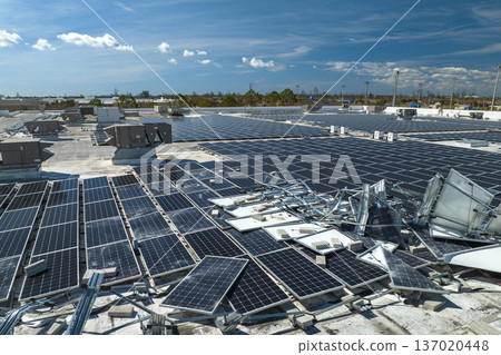 Aerial view of damaged by hurricane wind photovoltaic solar panels mounted on industrial building roof for producing green ecological electricity. Consequences of natural disaster Aerial view of damaged by hurricane wind photovoltaic solar panels mounted on industrial building roof for producing green ecological electricity. Consequences of natural disaster 137020448