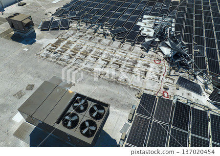Aerial view of damaged by hurricane wind photovoltaic solar panels mounted on industrial building roof for producing green ecological electricity. Consequences of natural disaster Aerial view of damaged by hurricane wind photovoltaic solar panels mounted on industrial building roof for producing green ecological electricity. Consequences of natural disaster 137020454