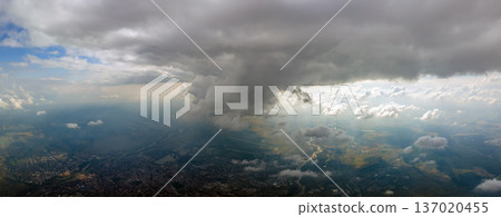 Aerial view from airplane window at high altitude of distant city covered with puffy cumulus clouds forming before rainstorm. Aerial view from airplane window at high altitude of distant city covered with puffy cumulus clouds forming before rainstorm. 137020455