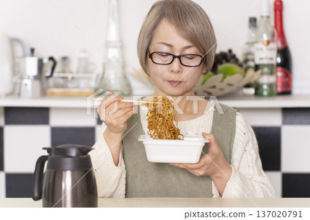 廚房裡,一位老婦人正往杯麵倒熱水。 廚房裡,一位老婦人正往杯麵倒熱水。 137020791