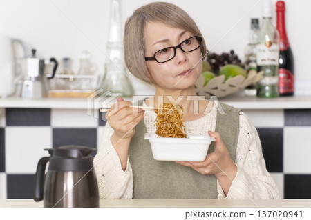 廚房裡,一位老婦人正往杯麵倒熱水。 廚房裡,一位老婦人正往杯麵倒熱水。 137020941