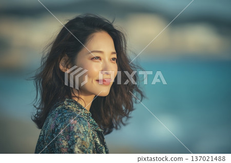 一張成年女性在海風中微笑的肖像照，她的肌膚在自然光下閃閃發光，散發著自由的氣息（橫幅照片） 137021488