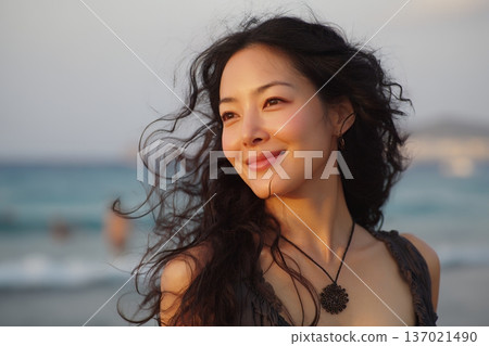一張成年女性在海風中微笑的肖像照，她的肌膚在自然光下閃閃發光，散發著自由的氣息（橫幅照片） 137021490