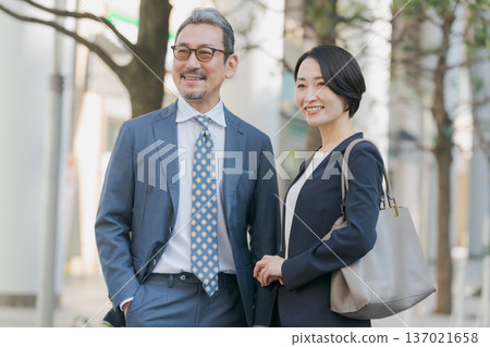 身著西裝的男女站在街角。 身著西裝的男女站在街角。 137021658