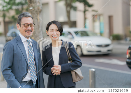 Men and women in suits standing on a street corner Men and women in suits standing on a street corner 137021659