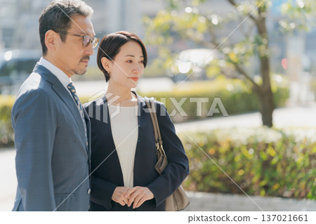 身著西裝的男女站在街角。 身著西裝的男女站在街角。 137021661